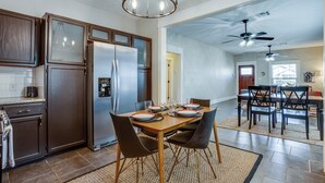 A spacious kitchen with dark wooden cabinets, a stainless steel refrigerator, and a dining area with a wooden table and chairs. - Chic Lawton Home, 5 Mins to Fort Sill! (Lawton)