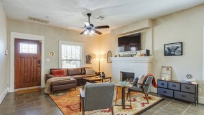 A spacious living room with a fireplace, a ceiling fan, and a large window. - Chic Lawton Home, 5 Mins to Fort Sill! (Lawton)