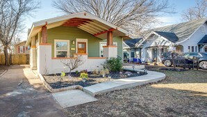 A single-story house with a green exterior and a red roof. It features a front porch with a bench and a small garden area. - Chic Lawton Home, 5 Mins to Fort Sill! (Lawton)