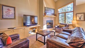 A living room with a fireplace, leather sofas, a TV, and framed artwork. - Walk to Lifts: 'chimney Ridge' Townhome w/ Hot Tub (Breckenridge)