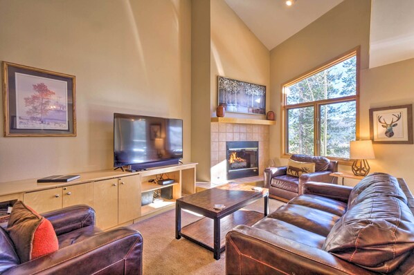 A living room with a fireplace, leather sofas, a TV, and framed artwork.