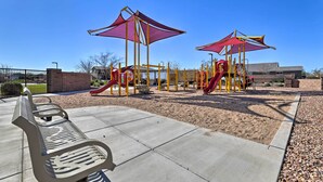 Ein Spielplatz mit Rutschen und Klettergerüsten, einer Bank und einem befestigten Sandbereich.