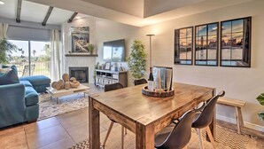 A spacious living area with a wooden dining table, blue sofa, and a fireplace. - Golf Course, Mountain Views: Scottsdale Condo! (Scottsdale)