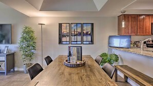 A dining area with a wooden table, chairs, a plant, a framed artwork, and a television. - Golf Course, Mountain Views: Scottsdale Condo! (Scottsdale)