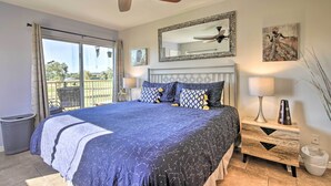 A bedroom with a large bed, ceiling fan, sliding glass doors to a balcony, and a nightstand with a lamp and vase. - Golf Course, Mountain Views: Scottsdale Condo! (Scottsdale)