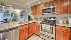 A modern kitchen with wooden cabinets, stainless steel appliances, granite countertops, and a dishwasher. - Golf Course, Mountain Views: Scottsdale Condo! (Scottsdale)