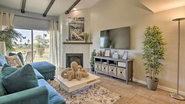 A modern living room with a sofa, coffee table, fireplace, TV, and potted plants. - Golf Course, Mountain Views: Scottsdale Condo! (Scottsdale)