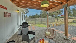 Ein überdachter Patio-Bereich mit Grill, Korbmöbeln und einer hängenden Leuchte.