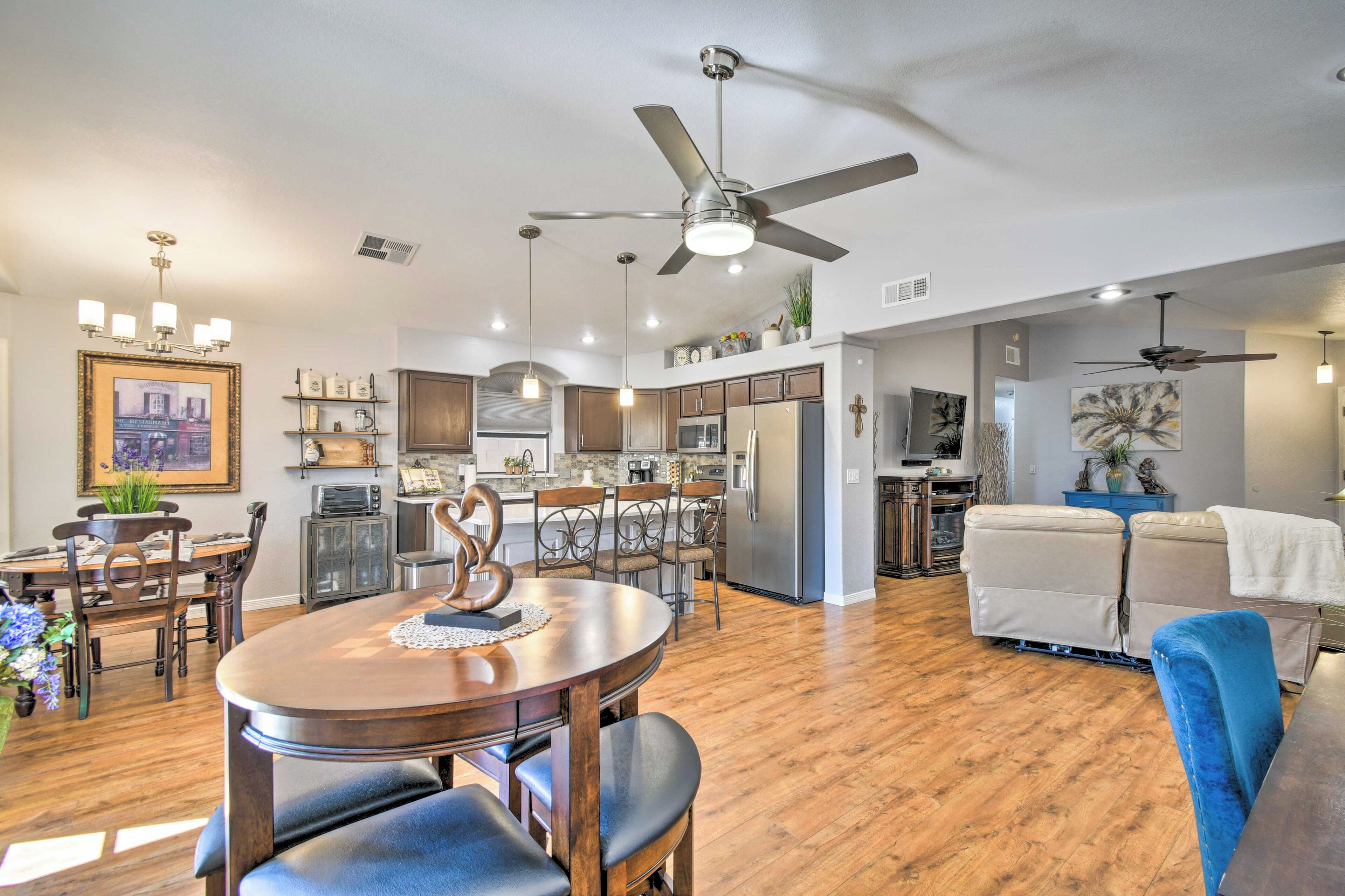A spacious living area with a dining table, sofas, and ceiling fans.