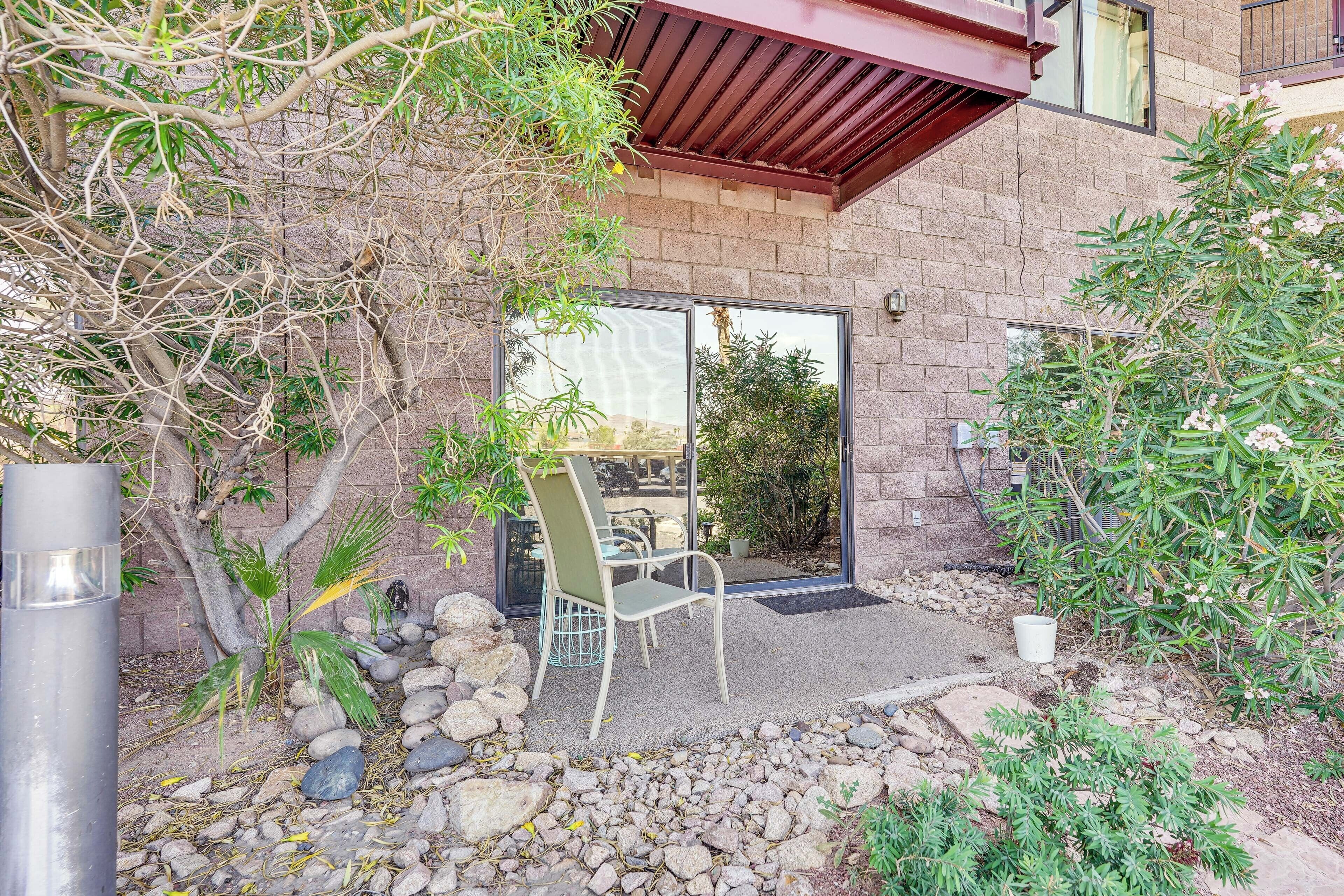 A patio with a table and chairs, surrounded by rocks and plants.