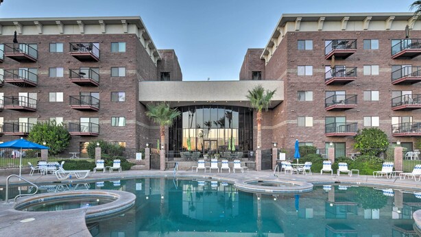 A hotel with a swimming pool, outdoor seating, and a modern brick facade.