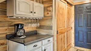 A kitchen with wooden walls, a coffee maker, and a cabinet with jars. - Granby Condo w/ Pool Access, Near Hiking & Skiing! (Granby)