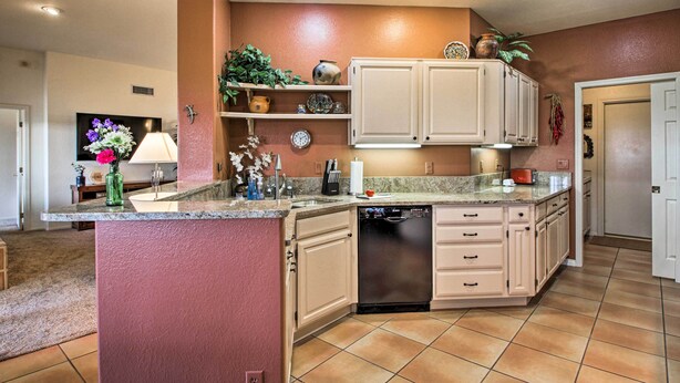A kitchen with white cabinets, a granite countertop, and a dishwasher. - Oro Valley Getaway w/ Patio, BBQ & Mountain Views! (Oro Valley)