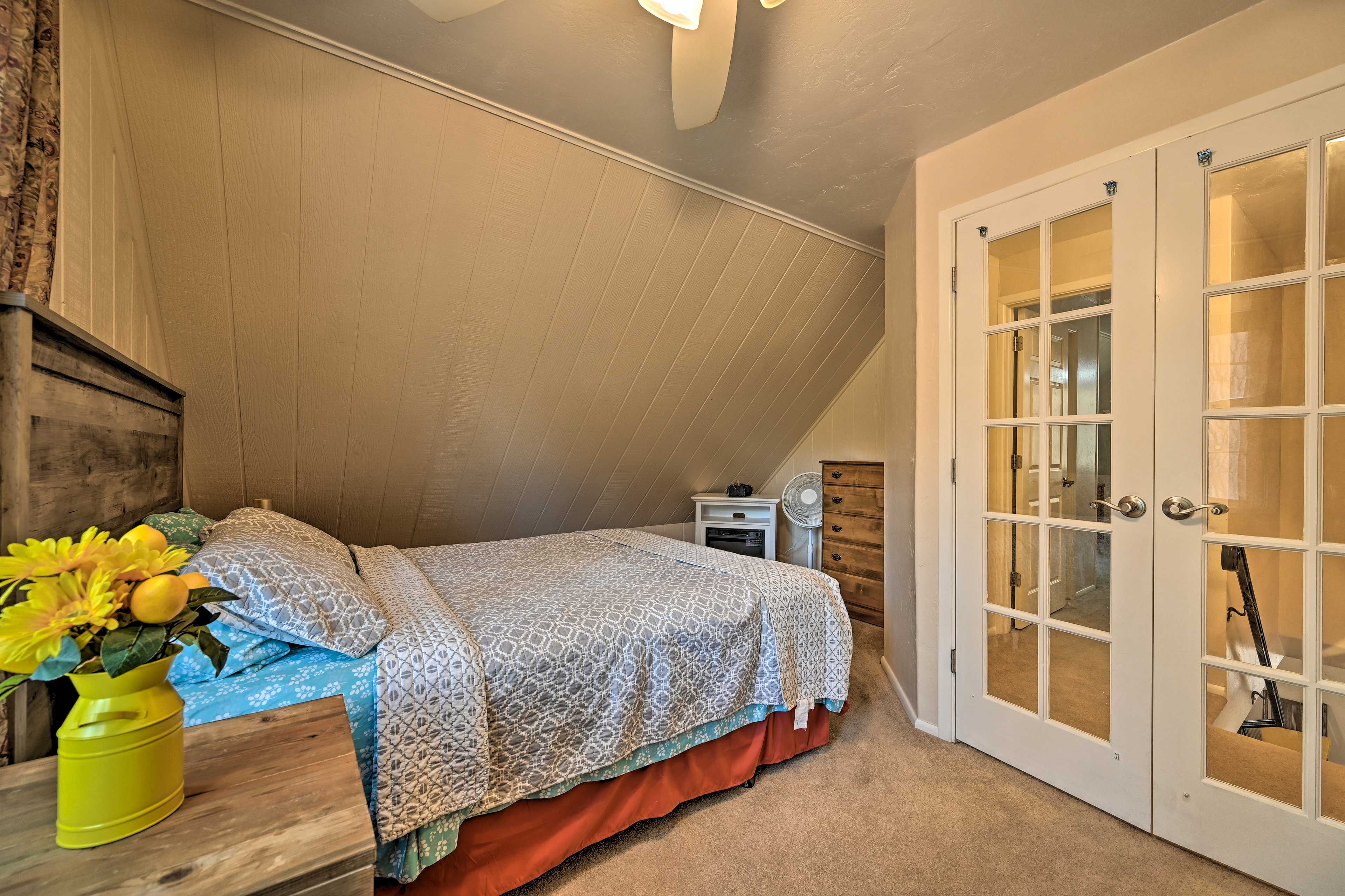 A bedroom with a bed, a nightstand, a dresser, and a door with glass panels.