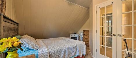 A bedroom with a bed, a nightstand, a dresser, and a door with glass panels.