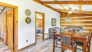A wooden interior with a dining table and chairs, a ceiling fan, and a bed in the background. - Rogersville Barn Apartment on 27 Acres w/ Pond! (Rogersville)
