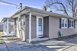 A single-story house with a front porch, a garage door, and a visible power outlet. - Buffalo Getaway w/ Charcoal Grill & Patio! (Buffalo)