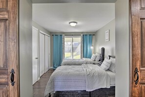 A bedroom with two beds, a window with curtains, a ceiling light, and a door with a handle. - Buffalo Getaway w/ Charcoal Grill & Patio! (Buffalo)