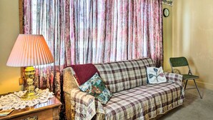 A cozy living room with a plaid sofa, a small wooden side table with a lamp, and a chair.