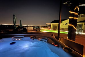 A hot tub with a view of a lit-up pool and a house in the background. - Casita 11 Mi to Dtwn: Pool, Spa, Hiking, Views (Laveen)