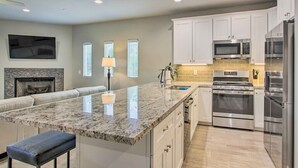 Una cocina moderna con armarios blancos, electrodomésticos de acero inoxidable y encimera de granito.
