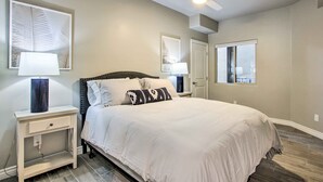 Un dormitorio con cama, mesitas de noche, ventilador de techo y obras de arte en las paredes.
