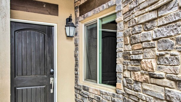 Una casa con una puerta de madera oscura, un muro de piedra y una ventana con marco verde.