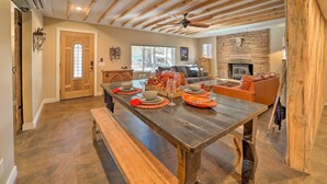 Una cocina amplia con una mesa de madera dispuesta para comer, una chimenea de piedra y una zona de estar acogedora con un sofá y cojines.