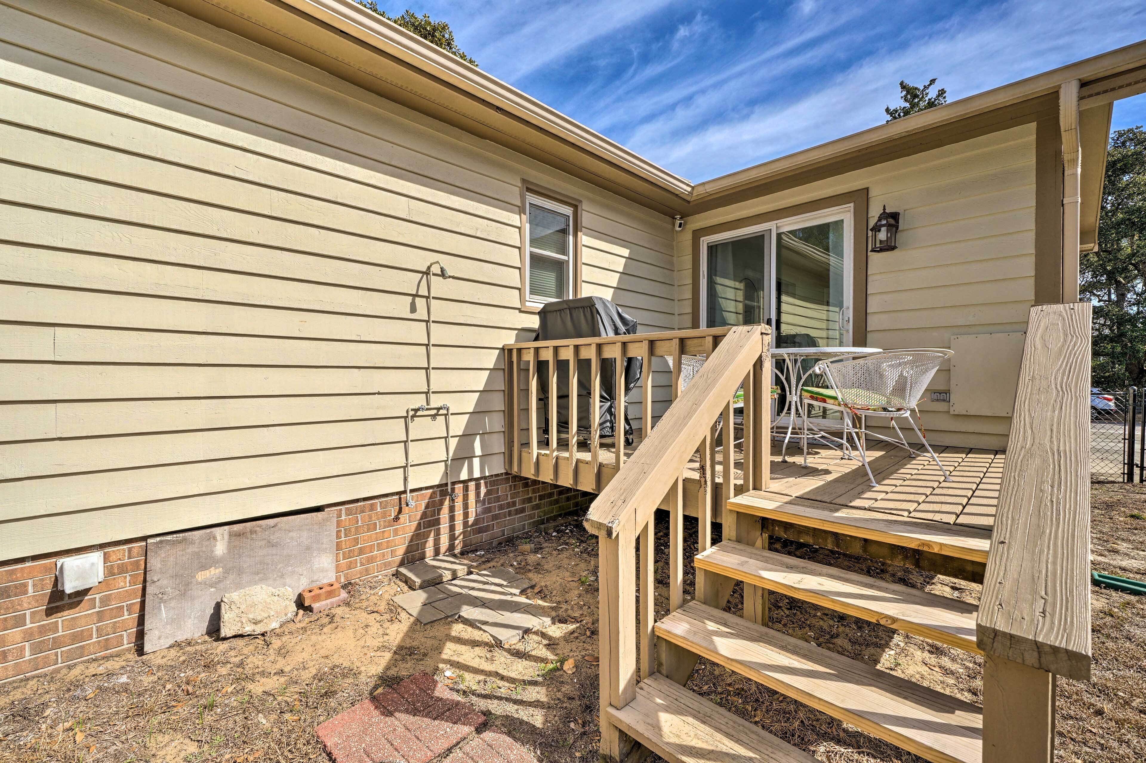 A wooden deck with a metal chair, a small table, and a grill.
