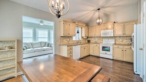 A spacious kitchen with wooden flooring, light-colored cabinets, a central island, and pendant lighting.