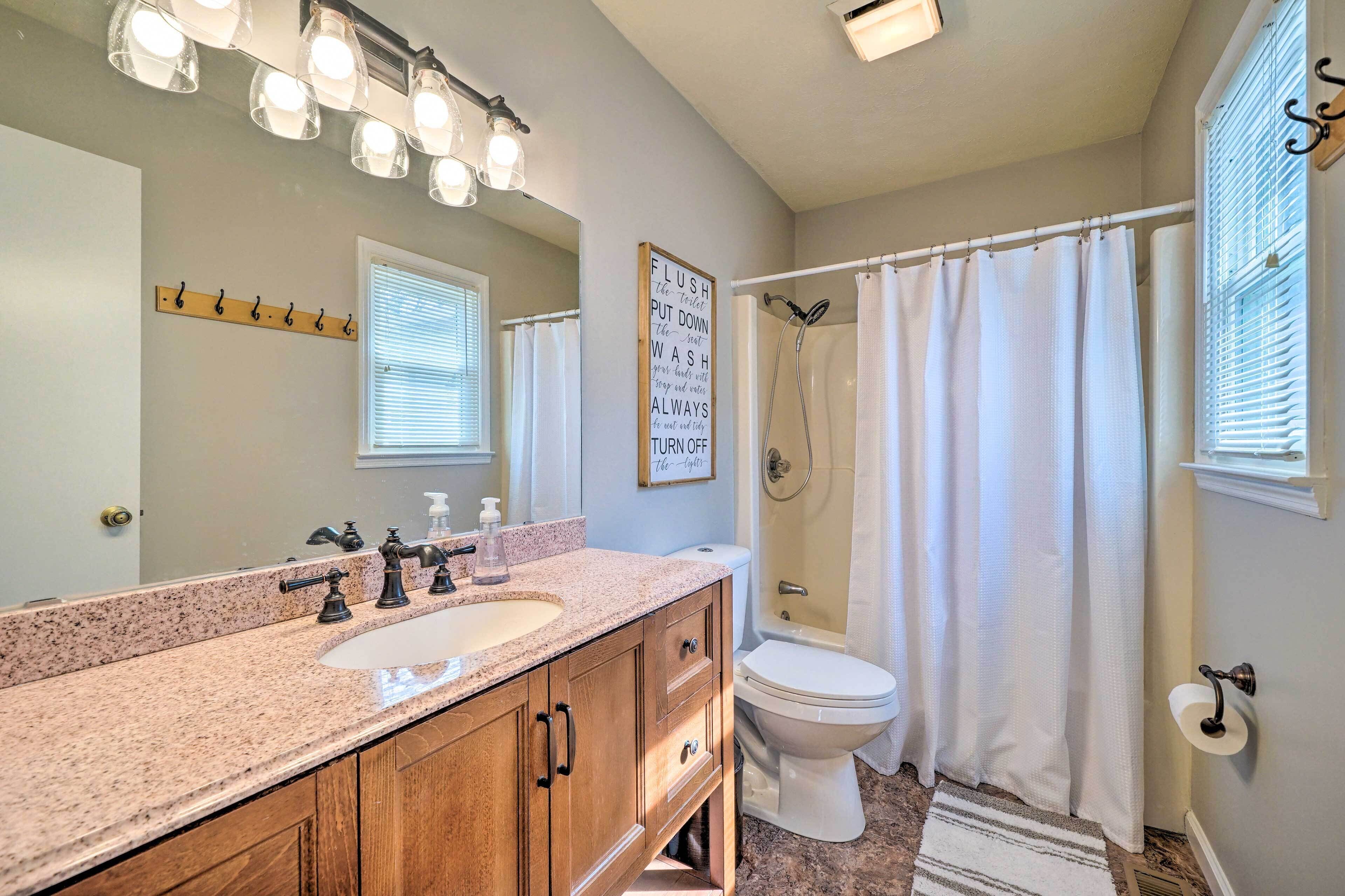 A bathroom with a double sink vanity, a toilet, a shower with a curtain, and a towel rack.
