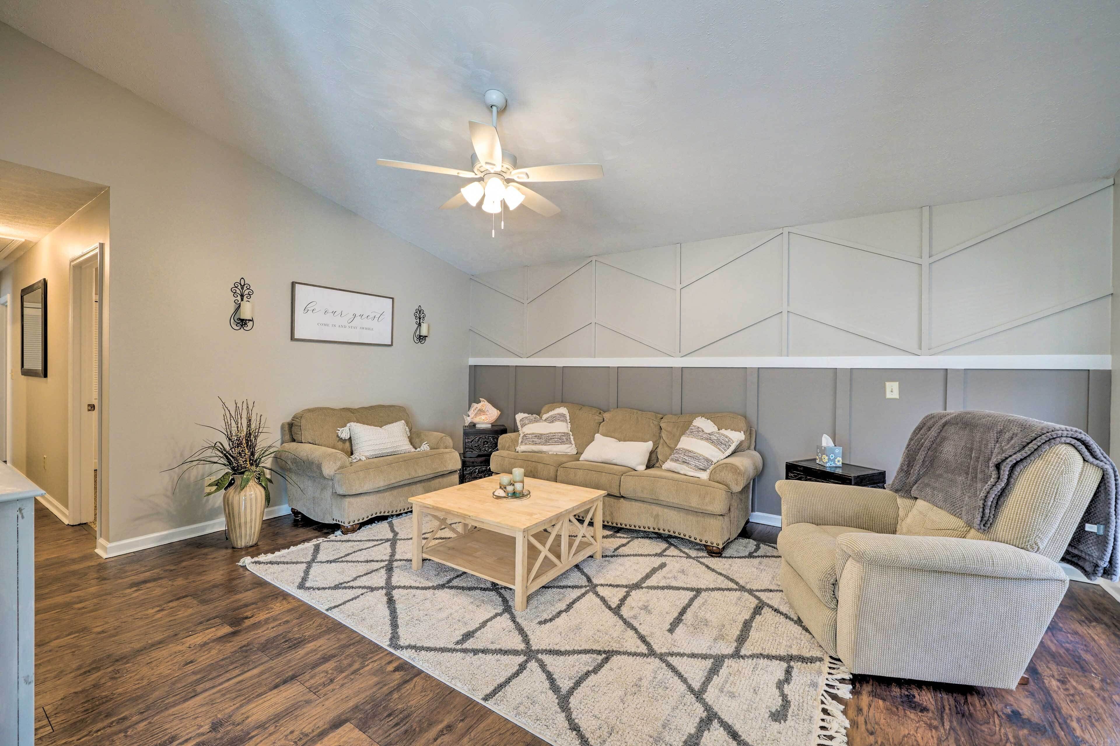 A living room with a ceiling fan, two sofas, a coffee table, and a patterned rug.