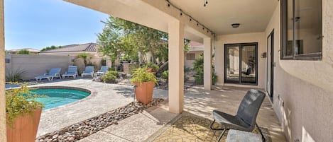 A covered patio with a pool, outdoor seating, and potted plants.