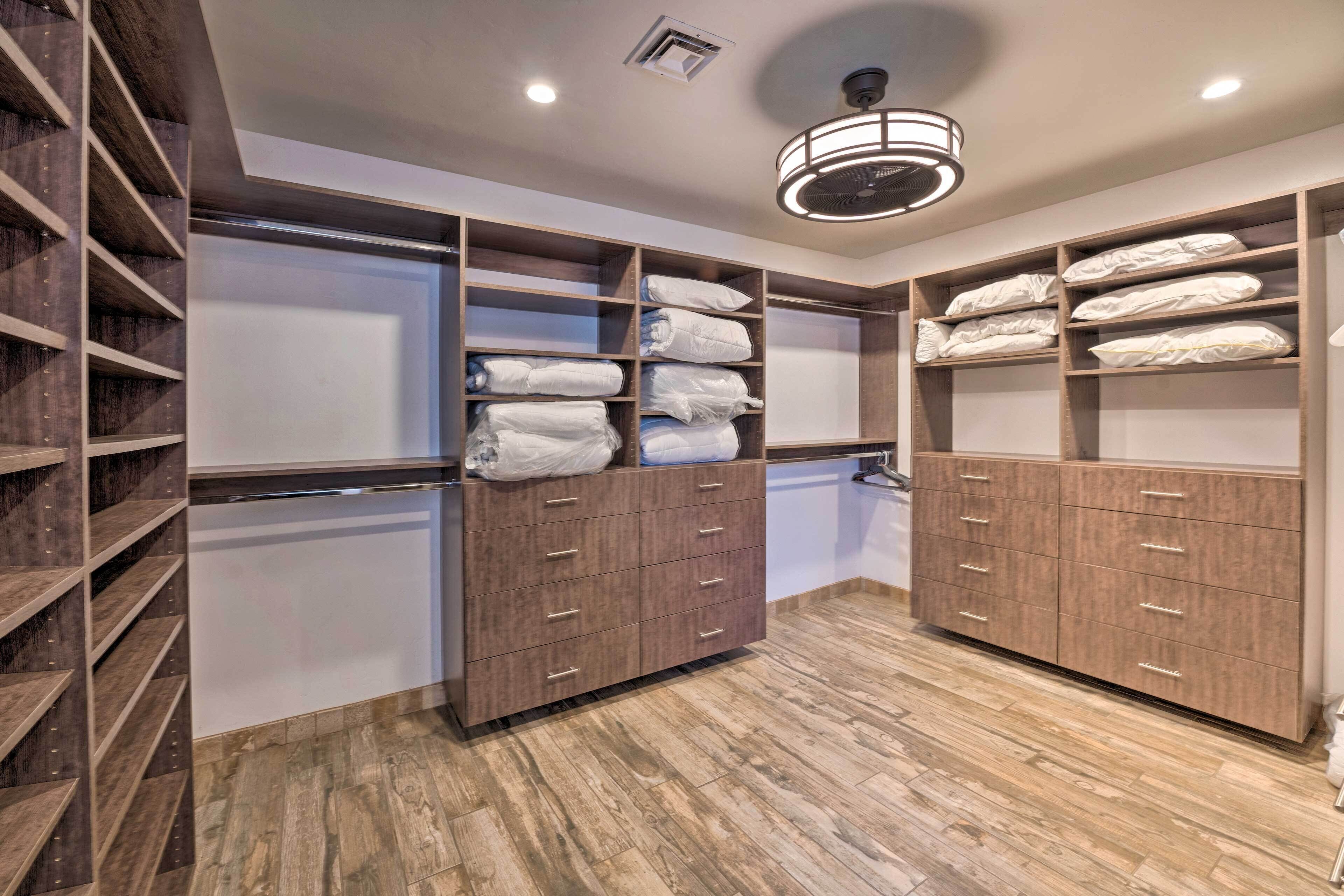 A walk-in closet with wooden shelving and drawers, containing neatly folded towels and robes.