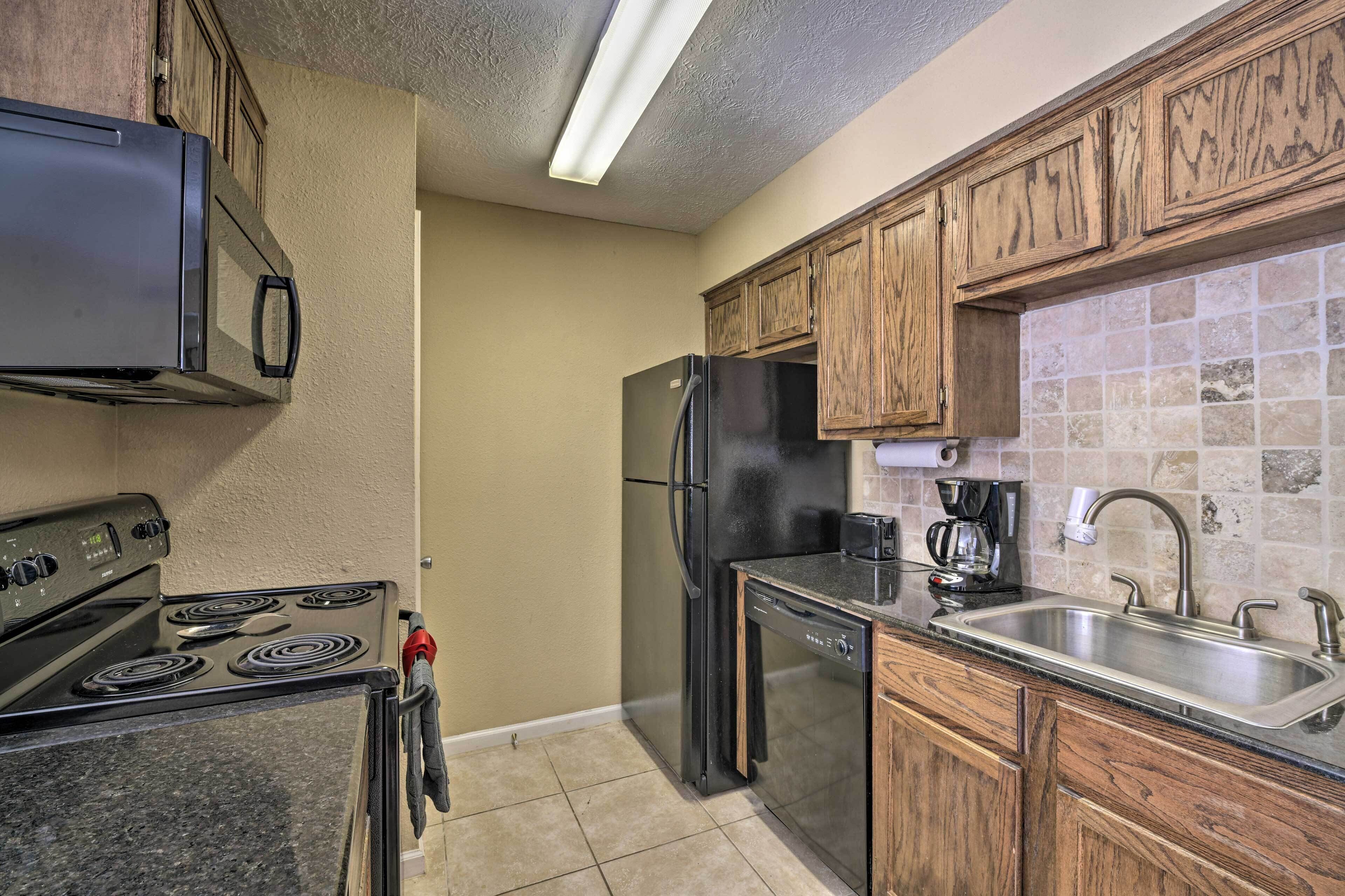 Una cocina con estufa, refrigerador, lavavajillas y armarios de madera.