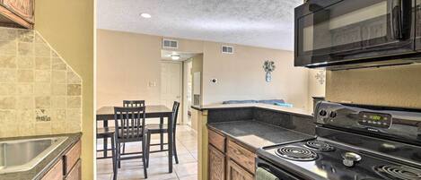 A kitchen with a black stove, a microwave, and a dining area with chairs and a table.
