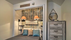 Un dormitorio con una cama, dos lámparas de noche, cabecera de madera, cómoda y espejo.