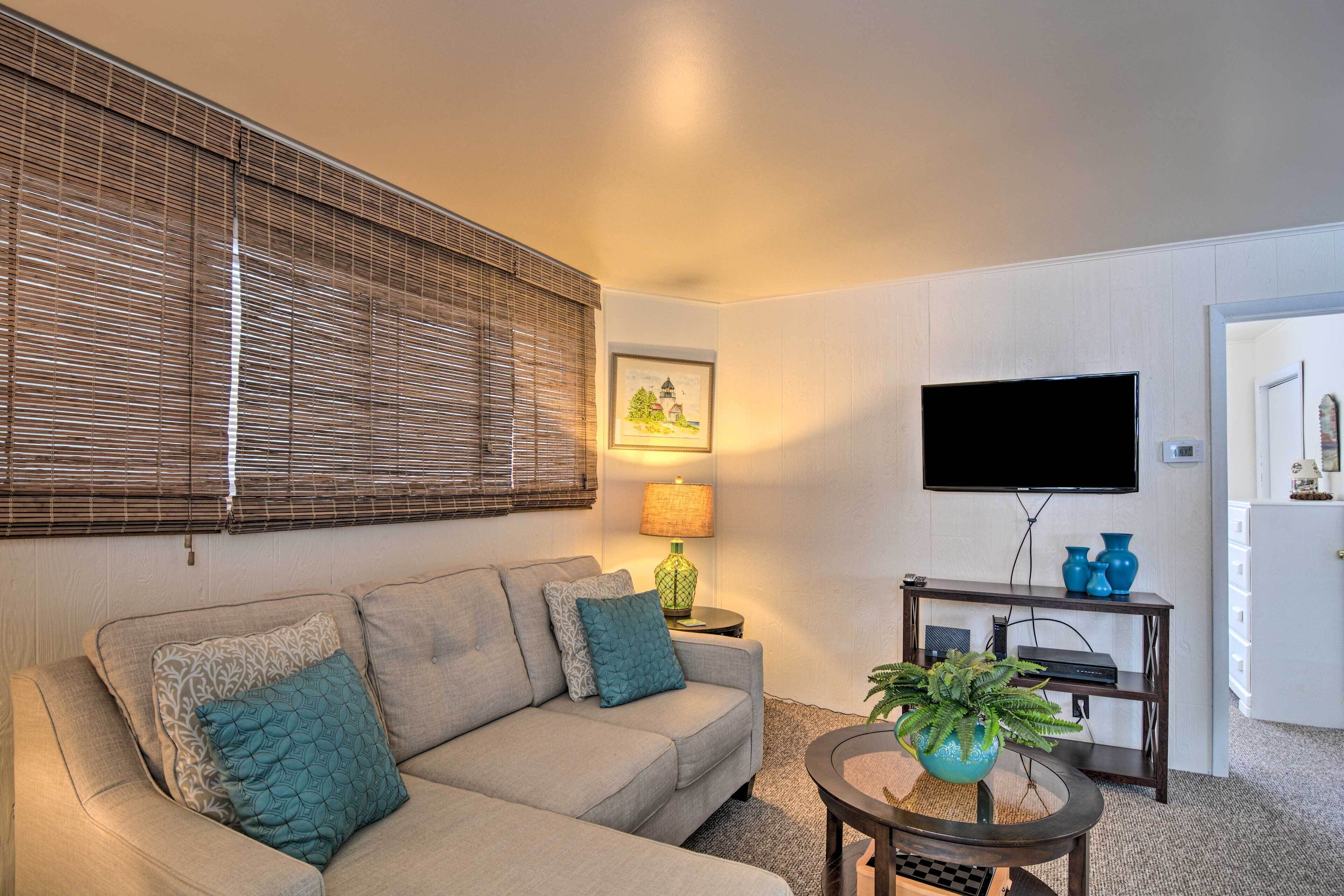 A living room with a sofa, a coffee table with a plant, a TV on the wall, and a lamp.