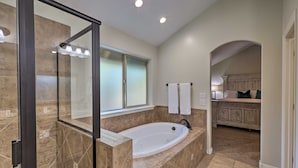 Une salle de bain moderne avec une grande baignoire, une douche à l’italienne et un meuble-lavabo avec un miroir.