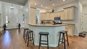 Una cocina amplia con una isla central, taburetes de madera y armarios de colores claros.
