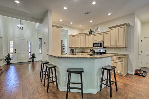 A spacious kitchen with a central island, wooden bar stools, and light-colored cabinetry. - 4 Mi to Downtown! Flagstaff Family Getaway (Flagstaff)