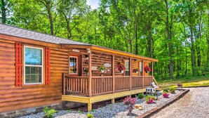 A wooden cabin with a porch, surrounded by a gravel driveway and a forested area. - 'almost Heaven Too' 50-acre Escape w/ Pond! (Brownsville)