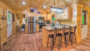 A wooden cabin with a kitchen featuring a refrigerator, stove, microwave, and bar stools. - 'almost Heaven Too' 50-acre Escape w/ Pond! (Brownsville)