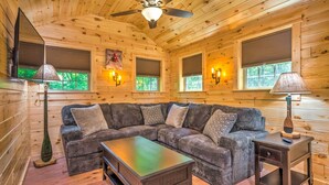 A cozy cabin interior with a sectional sofa, a coffee table, a side table, and a ceiling fan. - 'almost Heaven Too' 50-acre Escape w/ Pond! (Brownsville)