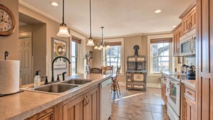 A spacious kitchen with wooden cabinets, a large island with a sink, and a vintage stove. - Pet-friendly Home: Grill & Fire Pit in Manhattan (Manhattan)