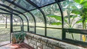 A conservatory with curved glass walls, a stone wall, and a tiled floor. - Pet-friendly Home: Grill & Fire Pit in Manhattan (Manhattan)