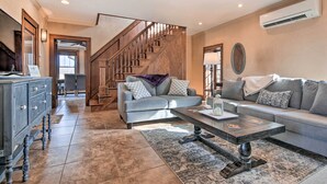 A spacious living room with a staircase, a sofa set, a coffee table, and a cabinet. - Pet-friendly Home: Grill & Fire Pit in Manhattan (Manhattan)