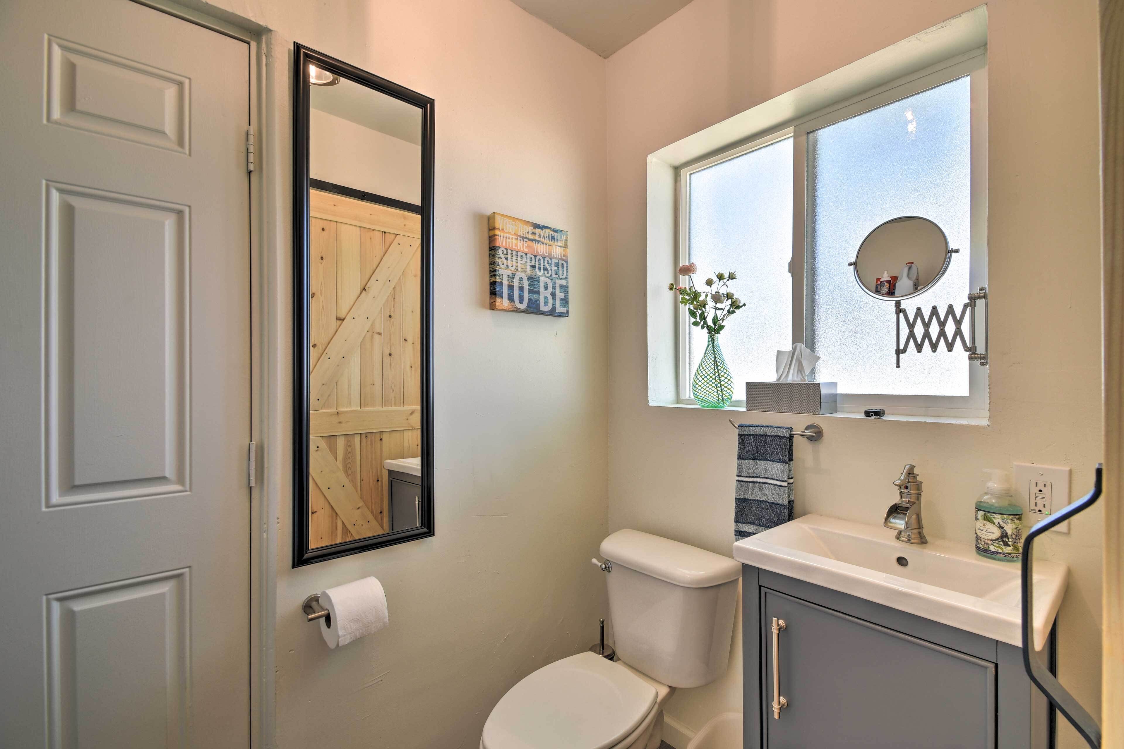 Un baño pequeño con inodoro, lavamanos y ventana con espejo.