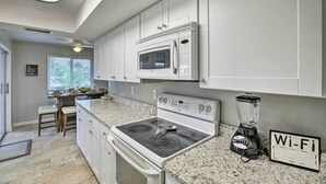 A kitchen with white cabinets, a stove, microwave, and a blender. - Bright Home w/ Dock & Canal View in Cape Coral! (Cape Coral)