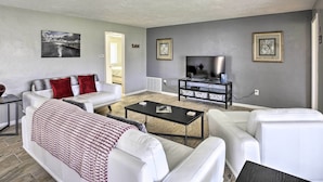 A modern living room with a white sofa, a black coffee table, and a flat-screen TV. - Bright Home w/ Dock & Canal View in Cape Coral! (Cape Coral)
